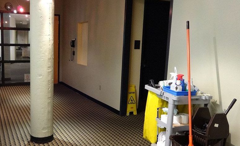 A janitorial cart and a caution sign in an office corridor