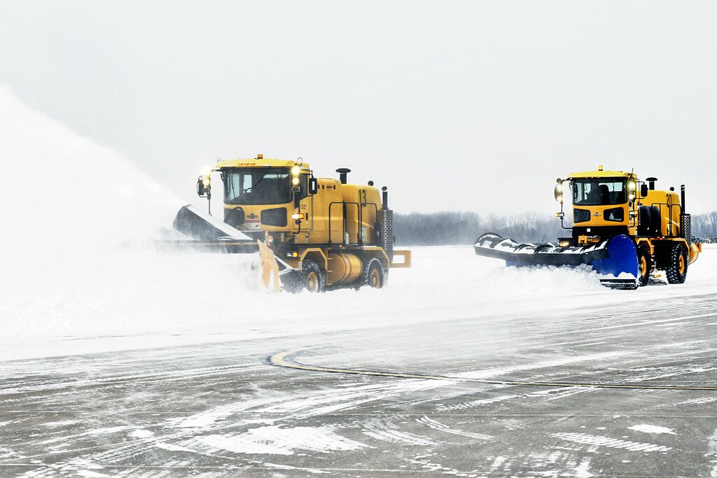 Two plows clear snow from an airfield